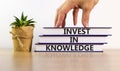 Time to invest in knowledge. Books with text `invest in knowledge` on beautiful white background. House plant, businessman hand.