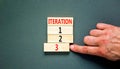 Time to iteration 3 symbol. Concept word Iteration 1 2 3 on wooden block. Businessman hand. Beautiful grey table grey background.