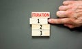 Time to iteration 1 symbol. Concept word Iteration 1 2 3 on wooden block. Businessman hand. Beautiful grey table grey background.