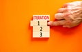 Time to iteration 1 symbol. Concept word Iteration 1 2 3 on wooden block. Businessman hand. Beautiful orange table orange