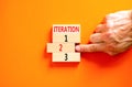 Time to iteration 2 symbol. Concept word Iteration 1 2 3 on wooden block. Businessman hand. Beautiful orange table orange