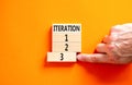 Time to iteration 3 symbol. Concept word Iteration 1 2 3 on wooden block. Businessman hand. Beautiful orange table orange