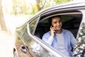 Time to make decision. Confident young businessman working on his laptop and talking on the phone while sitting in the car Royalty Free Stock Photo