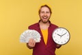 Time to make money! Happy cheerful hipster bearded guy in checkered shirt holding big clock and dollars
