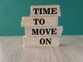 Time to move on - concept words on brick blocks on wooden table. Green background.