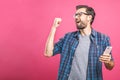 Time to relax. Handsome young man in headphones keeping eyes closed while dancing. Over pink background. Isolated Royalty Free Stock Photo