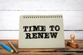 Time to Renew. Green notepad on wooden texture table and white background