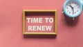 Time to renew , text in a gold frame on a pink background, near an alarm clock. Business, strategies, plans Royalty Free Stock Photo