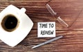 TIME TO RENEW text on sticky with coffee,pen and glasses on the wooden background Royalty Free Stock Photo