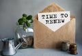 TIME TO RENEW text is written on white paper on an antique envelope, which lies on the table along with a stack of coins, a glass Royalty Free Stock Photo