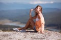 Time to rest. Relaxing moment. Contemplation and dreaming. Smiling woman sitting on rock and looking away thoughtfully Royalty Free Stock Photo