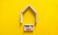 Time to sell house symbol. Concept words `Time to sell` on wooden blocks near miniature house. Beautiful yellow background, copy Royalty Free Stock Photo