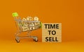 Time to sell real estate symbol. Wooden blocks, words `time to sell` on beautiful orange background. Shopping cart with miniatur