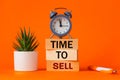 Time to sell symbol. alarm clock and time to sell, word concept on wooden blocks. Beautiful orange background, succulent on desk, Royalty Free Stock Photo