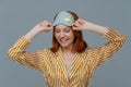 Time to sleep or go to bed. Glad ginger woman keeps gaze down, wears sleepmask and sleepwear, has happy expression, enjoys good