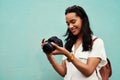 Time to snap some pictures. an attractive young woman standing alone against a blue background in the city and holding