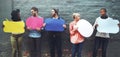 Time to speak up. a diverse group of people holding up speech bubbles against a gray brick wall. Royalty Free Stock Photo