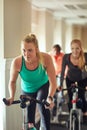Time to sweat it out in spin class. a young woman working out with an exercise bike in a spinning class at the gym. Royalty Free Stock Photo