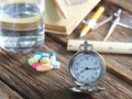 Time to take medicine. Pocket watch, Colorful medicine, water glasses, stationery and stationery. On the old wood table, meaning d Royalty Free Stock Photo