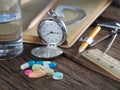 Time to take medicine. Pocket watch, Colorful medicine, water glasses, stationery and stationery. On the old wood table, meaning d Royalty Free Stock Photo