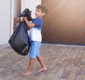 Time to take out the trash. Shot of a little boy taking out the trash at home. Royalty Free Stock Photo