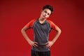 Time to train. A teenage boy is engaged in fitness, he is looking at camera while doing exercise. Isolated on red Royalty Free Stock Photo