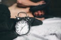 Time to wake up. Tired man in the bed not happy. Mature guy holding alarm clock while checking time for work Royalty Free Stock Photo