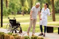 The doctor helps the patient to walk on crutches. Wheelchair left behind