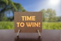 Time to win text on card on the table with sunny green park background Royalty Free Stock Photo