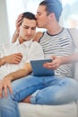 Time together is always a good time. Shot of an affectionate gay couple using a digital tablet while relaxing on the Royalty Free Stock Photo