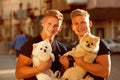 Time for a walk. Muscular men with dog pets. Twins men hold pedigree dogs. Happy twins with muscular look. Spitz dogs