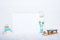 Blank notepad, teddy bear with snowballs, toy wooden blue skis, sledges and white hat on snowy background Royalty Free Stock Photo