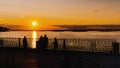 Timelapse - couple admiring dramatic colorful golden susnet on river at quay