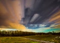 Timelapse movement of clouds towards woods across a field of crops