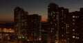 Timelapse of sunset to night transition over high-rise buildings with window lighs cityscape