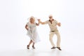 Portrait of retro style dancers, senior man and woman in vintage attire dancing swing  on white background Royalty Free Stock Photo