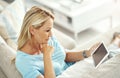 Timeout with her tablet. an attractive mature woman relaxing on the sofa with a digital tablet.