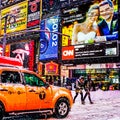 Times Square with yellow New York City Taxi cabs and tour buses driving through colorful billboards in the winter snowstorm