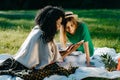 Timespending of two cheerful young attractive girl friends. The adorable african girl is showing something funny on her Royalty Free Stock Photo