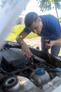 Timing belt break. Man near hood of car is looking for a malfunction due to which the engine does not work. Driver is holding a Royalty Free Stock Photo