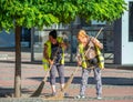 Two municipal female worker sweeping the pavement with broomstick, in the center of Timisoara