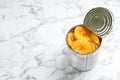 Tin can with conserved peach halves on marble background