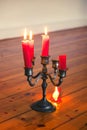 Tin candleholder with bruning red candles and dripping wax on wooden floor Royalty Free Stock Photo