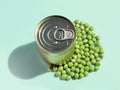 Tin cans closed surrounded fresh green peas, on light background