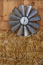 Tin clock sitting on a bale of hay