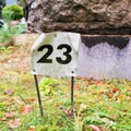 Plate with a number 23 sticked into the ground.