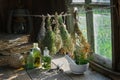 Tincture or infusion bottles, old books, mortar and hanging bunches of dry medicinal herbs. Royalty Free Stock Photo