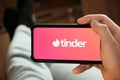 Tinder logo on the smartphone screen in mans hand. Man using tinder application for dating and looking for love, July