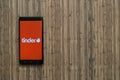 Tinder logo on smartphone screen on wooden background.