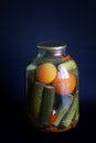 Tinned cucumbers and tomatoes in a large three-liter jar on a dark blue background. Farm harvest and homemade products concept